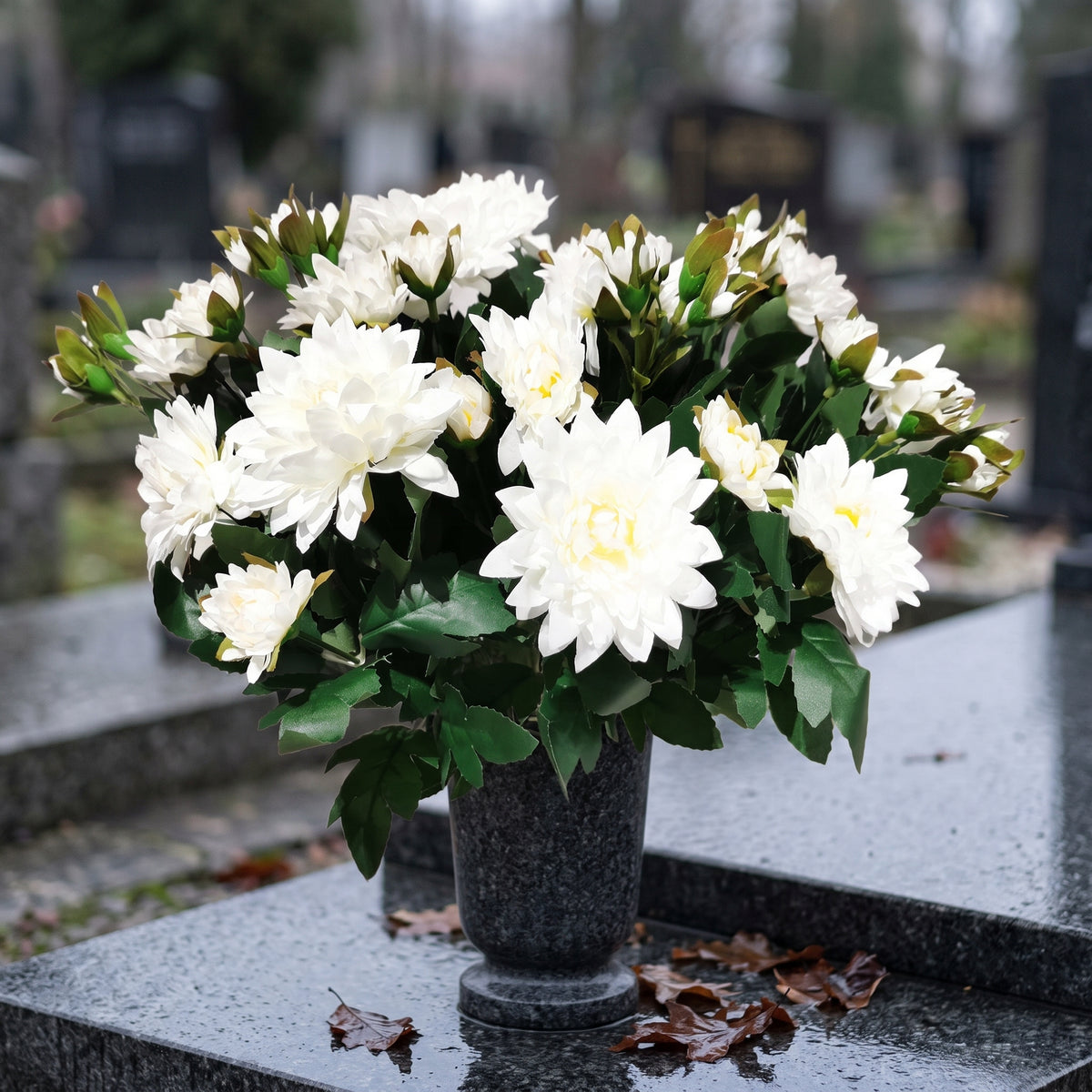 Biała chryzantema sztuczna w granitowym wazonie na grobie, listopadowe światło
